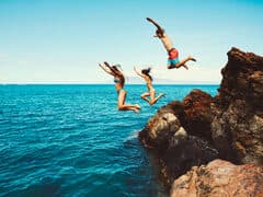 Travellers cliff jumping into the ocean